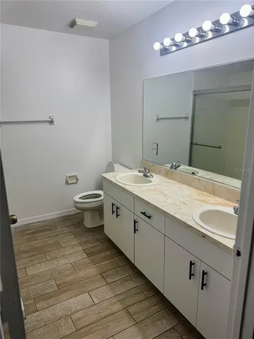 a spacious bathroom with a double vanity sink a toilet and a mirror