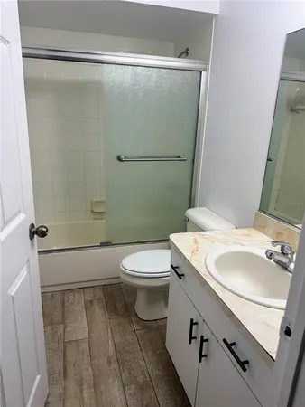 a bathroom with a sink a toilet a mirror and shower