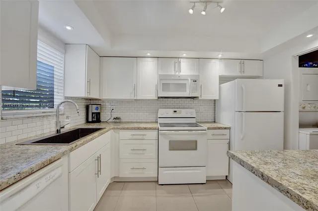 a kitchen with granite countertop white cabinets and white appliances