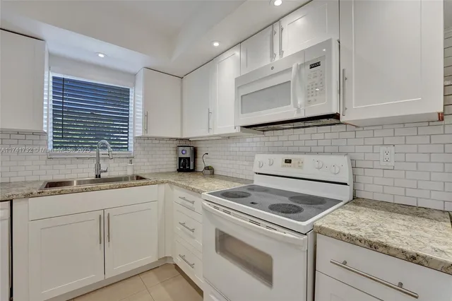 a kitchen with cabinets appliances a sink and a window