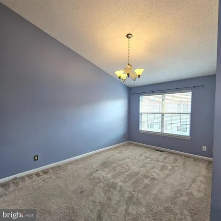 a view of an empty room with window and chandelier fan