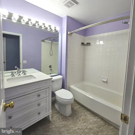 a bathroom with a sink vanity mirror bathtub and toilet