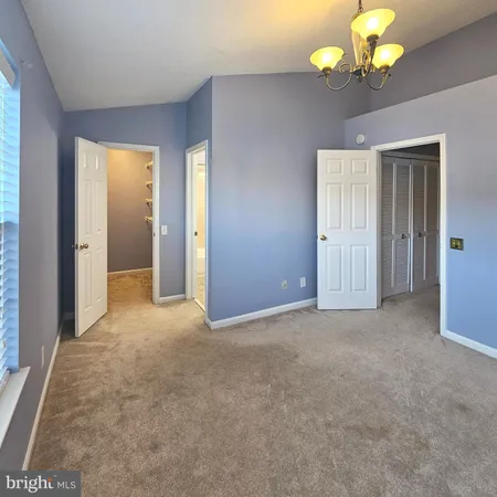 a view of an empty room with a chandelier fan