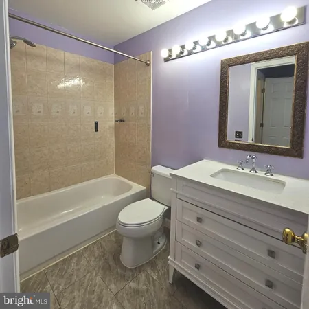a bathroom with a bathtub shower sink vanity and toilet