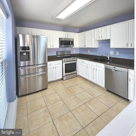 a kitchen with granite countertop a refrigerator and a stove top oven