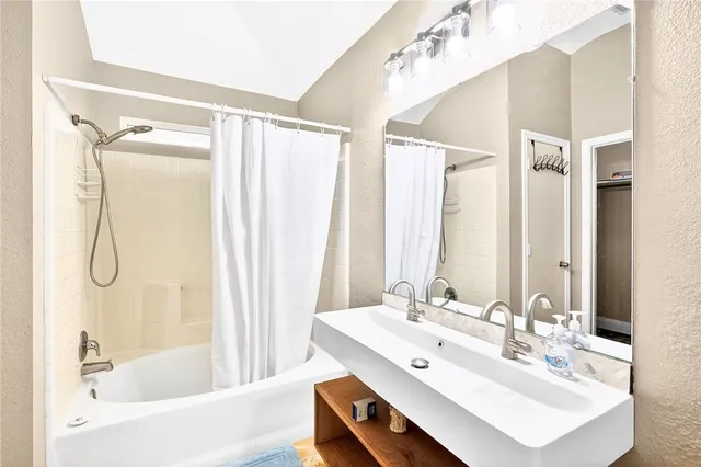 a bathroom with a bathtub shower sink and a mirror