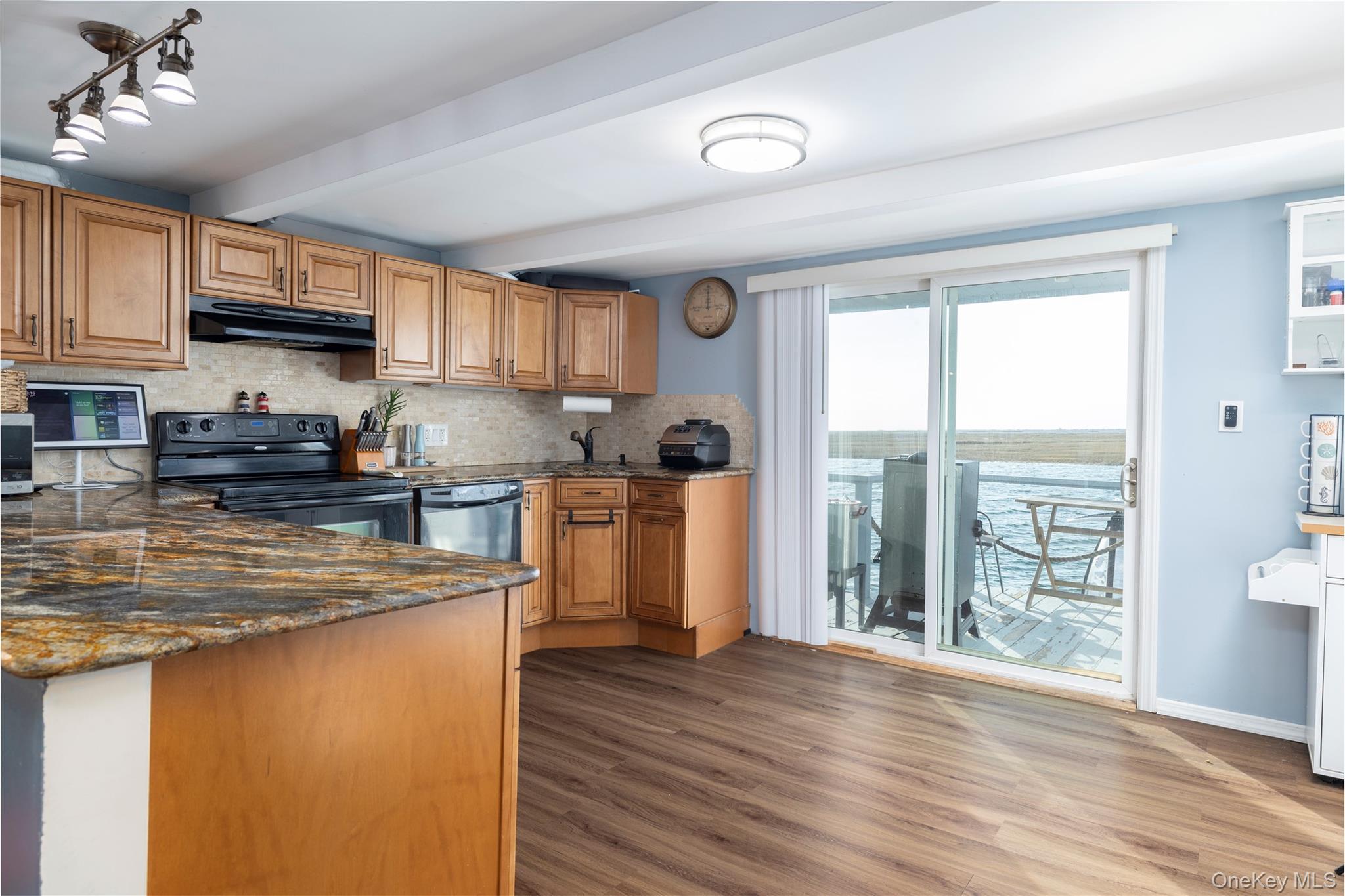 220 Shore Road Seaford, NY 11783 - Photo 10 of 23 a kitchen with stainless steel appliances granite countertop a stove a sink dishwasher a refrigerator and a dining table with wooden floor