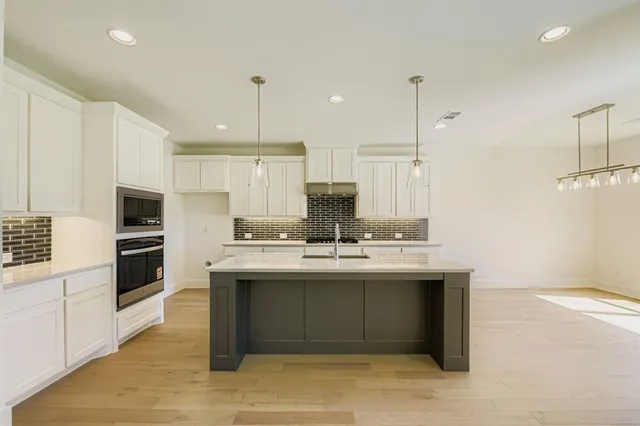 a kitchen with a sink a stove a refrigerator and white cabinets with wooden floor