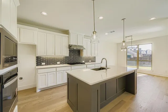 a large white kitchen with a large window a sink and stainless steel appliances