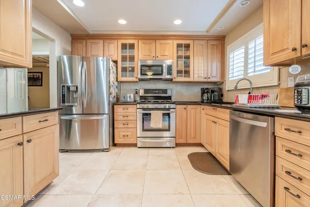 a kitchen with stainless steel appliances granite countertop a refrigerator and a stove top oven