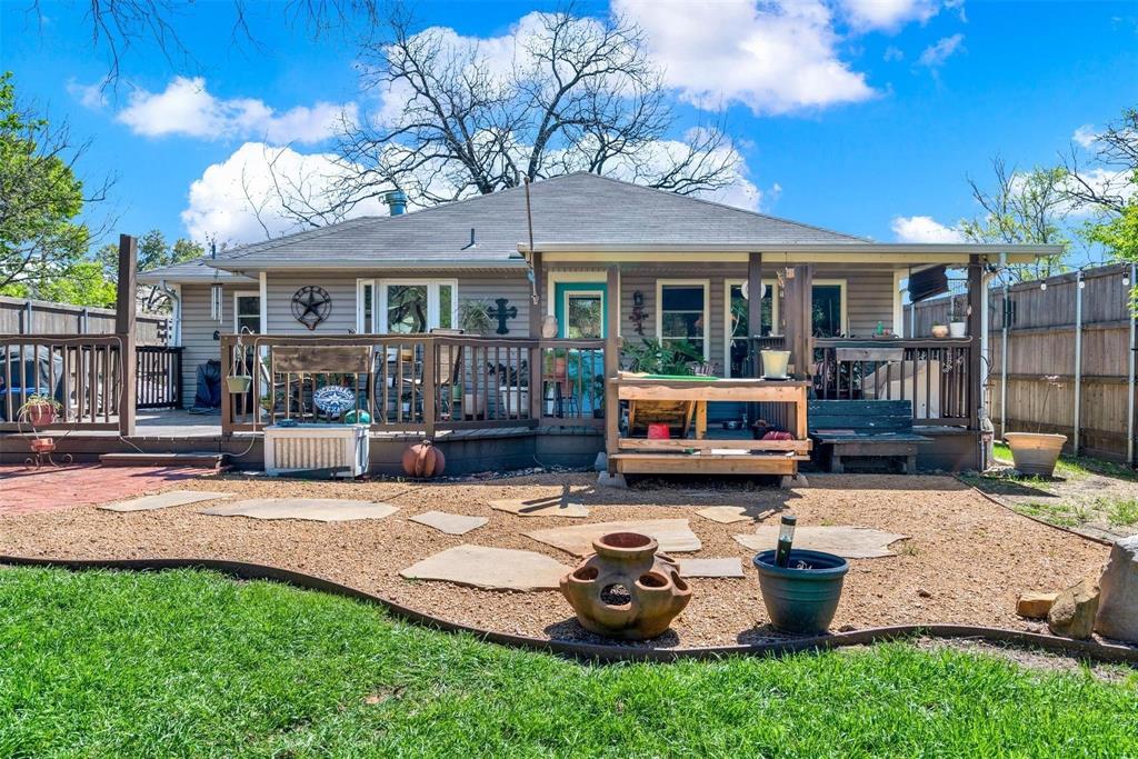 319 East Spring Valley Road Richardson, TX 75081 - Photo 21 of 22 Expansive wooden deck with railing, covered patio area, gravel hardscaping with stone pavers, and a manicured lawn