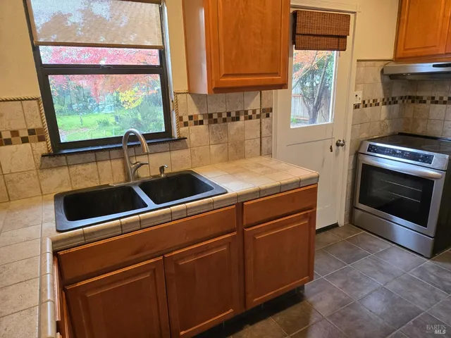 a kitchen with stainless steel appliances a stove sink and window