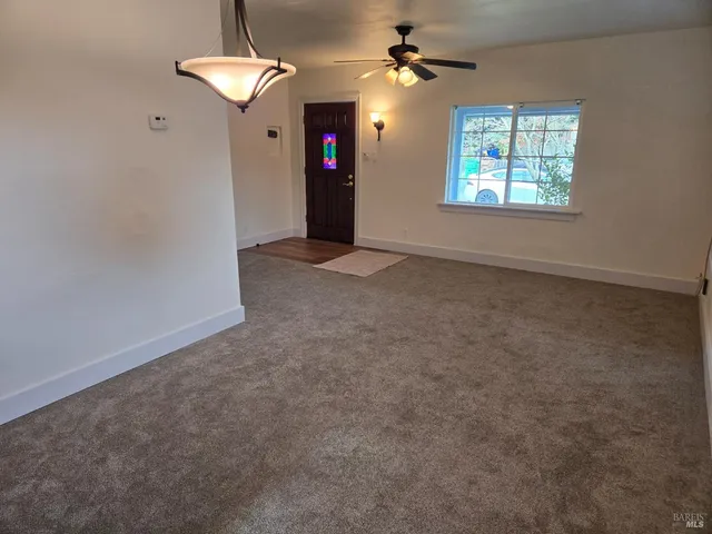 an empty room with windows and fan