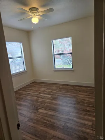 a view of an empty room with a window and wooden floor
