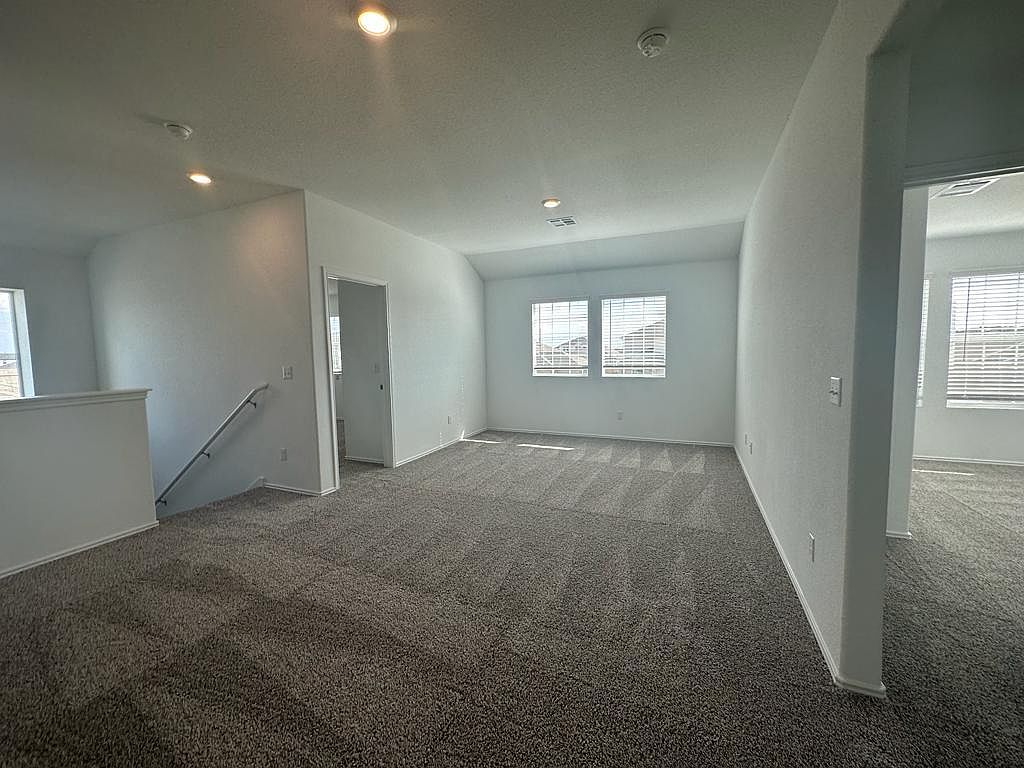 160 River Rise Road Kyle, TX 78640 - Photo 19 of 35 Spacious carpeted room featuring multiple windows with blinds, recessed lighting, and a neutral color palette