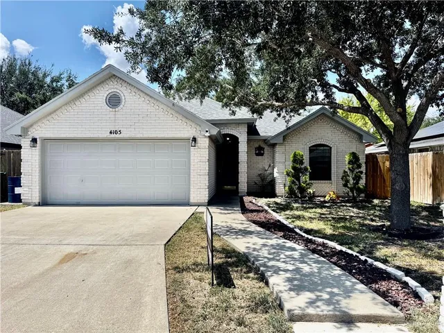 a view of house and yard with trees in the background