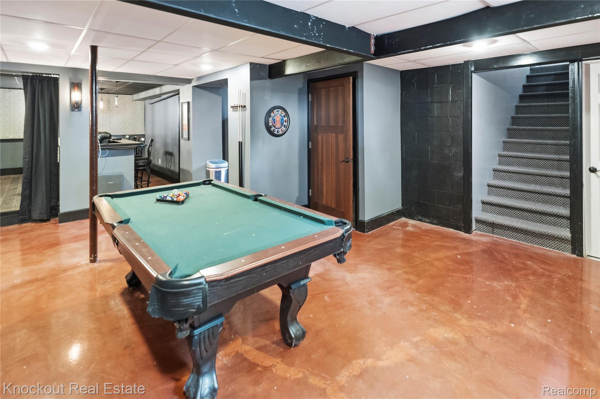 5750 Maple Road Frankenmuth, MI 48734 - Photo 35 of 60 Expansive recreation room featuring polished concrete flooring, a built-in wet bar, wood-paneled door, and carpeted stairs