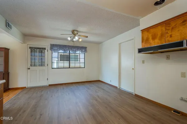 an empty room with wooden floor chandelier and windows