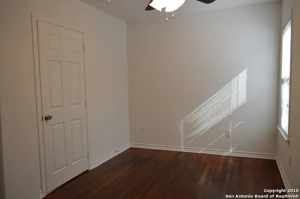 an empty room with wooden floor cabinet and windows