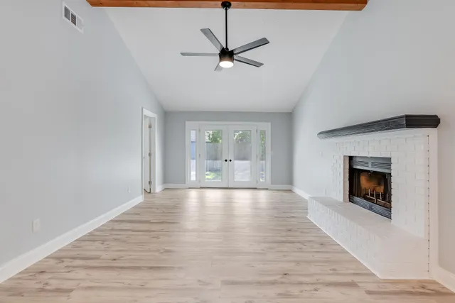 a view of an empty room with a fireplace and a window