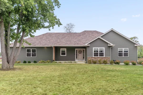 a front view of house with yard and trees in the background