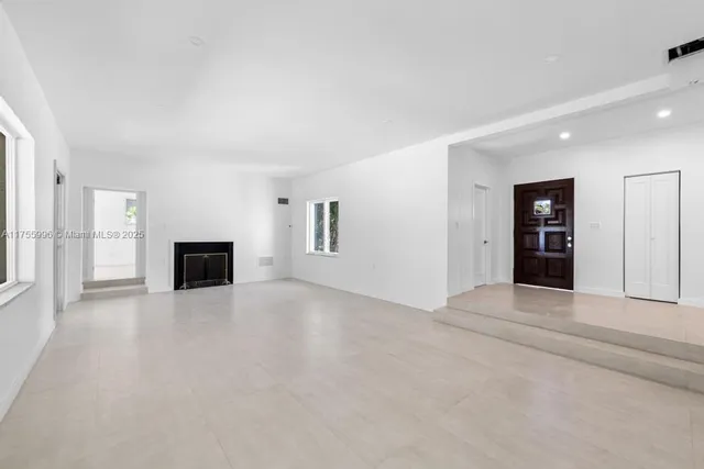 a view of an empty room with a fireplace and a window