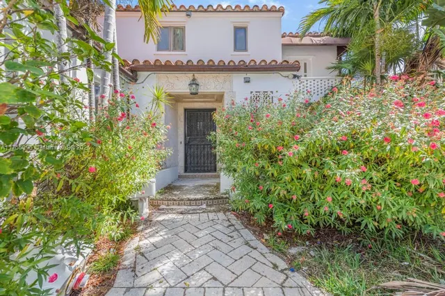 front view of a house with a yard and potted plants