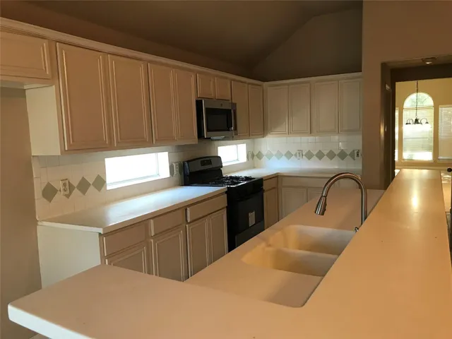 a kitchen with granite countertop a stove a sink and a microwave
