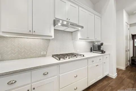 a kitchen with white cabinets and a stove with wooden floor
