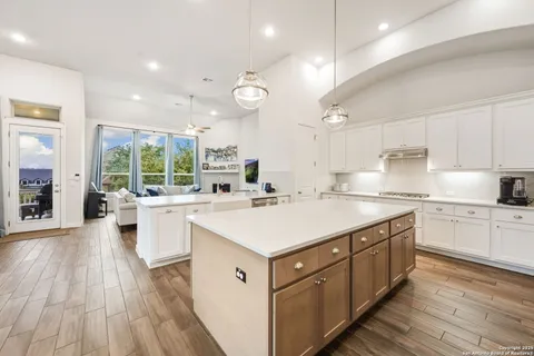 a kitchen with a stove a sink a refrigerator and white cabinets with wooden floor