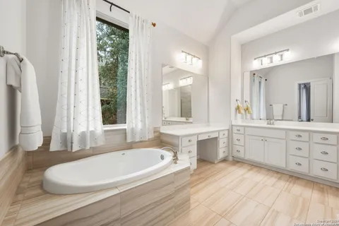 a bathroom with a granite countertop sink and a bathtub