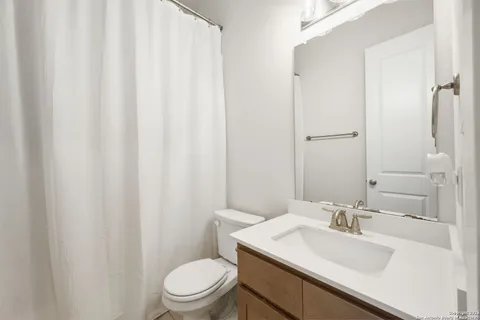 a bathroom with a sink a toilet and shower curtain