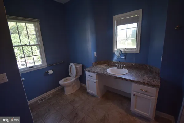 a bathroom with a granite countertop sink toilet and mirror