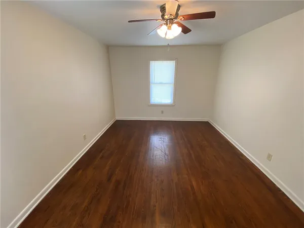 an empty room with wooden floor chandelier fan and windows