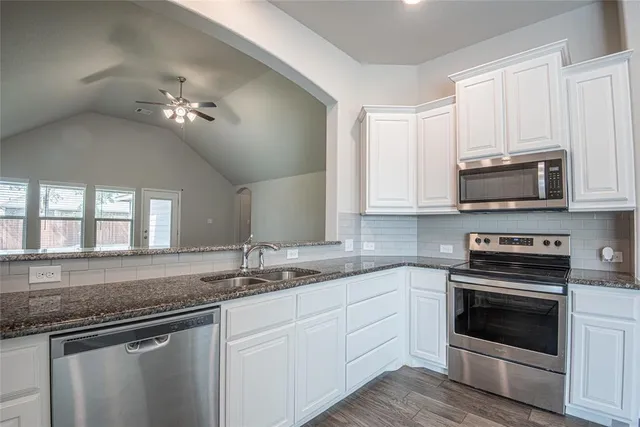 a kitchen with stainless steel appliances granite countertop a sink dishwasher a stove and a microwave oven with cabinets