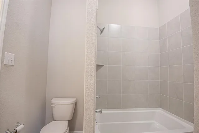 a white toilet sitting next to a bath tub