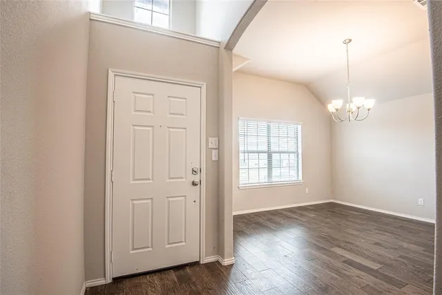 an empty room with wooden floor cabinet and windows