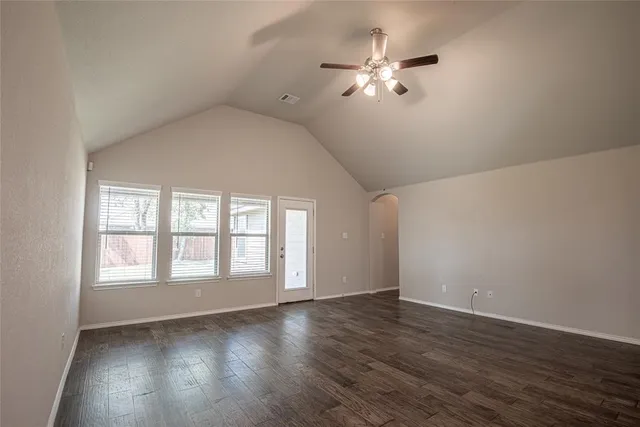 an empty room with wooden floor chandelier fan and windows