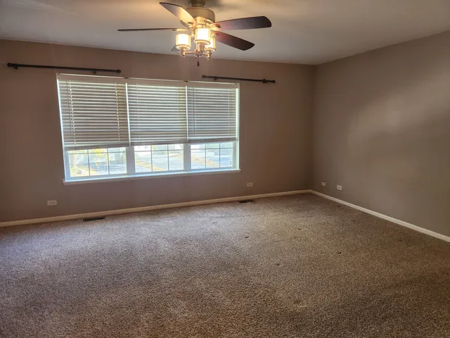 an empty room with a window and a fan