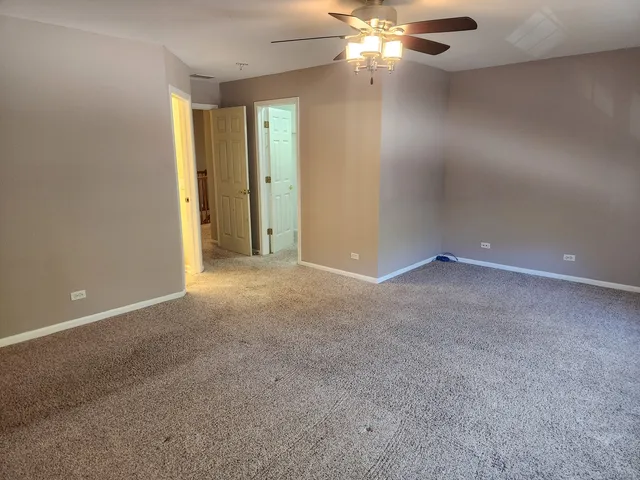 a view of an empty room with a chandelier fan