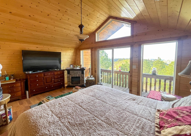 2498 West Silverado Ridge Alton, UT 84710 - Photo 17 of 51 Bedroom with wooden walls, wood ceiling, wood finished floors, access to outside, and a fireplace