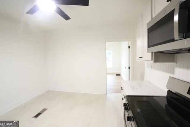 a kitchen with white cabinets appliances a sink and a window