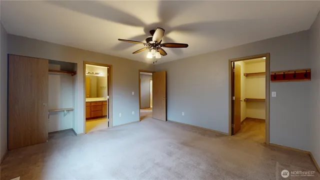 an empty room with closet and a ceiling fan