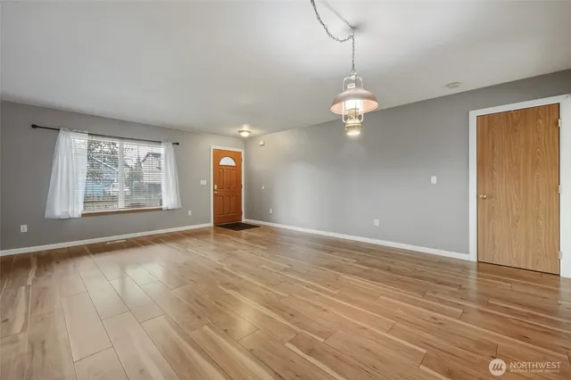 an empty room with wooden floor chandelier and windows