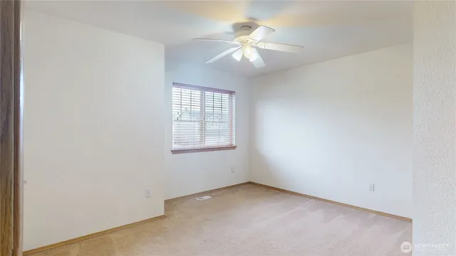 an empty room with windows and fan
