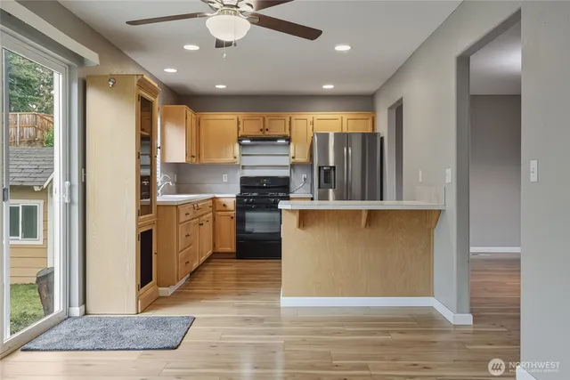 a view of kitchen with stainless steel appliances granite countertop a stove top oven a sink and a refrigerator