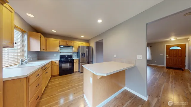 a large kitchen with stainless steel appliances kitchen island a large counter top and a wooden floors