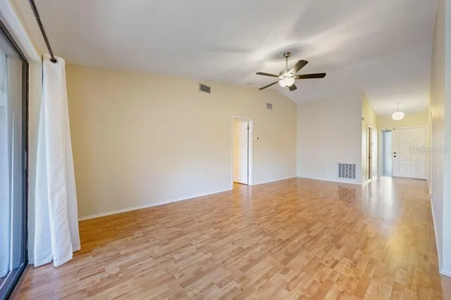 a view of empty room with wooden floor and fan