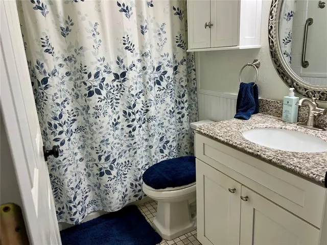 a bathroom with a granite countertop sink a toilet and a mirror