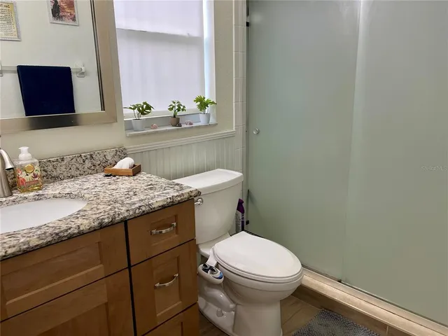 a bathroom with a granite countertop toilet sink and mirror
